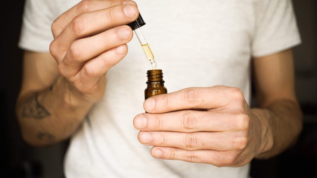 This image shows a man dispensing Nature's Candy CBD tincture oil before consuming.