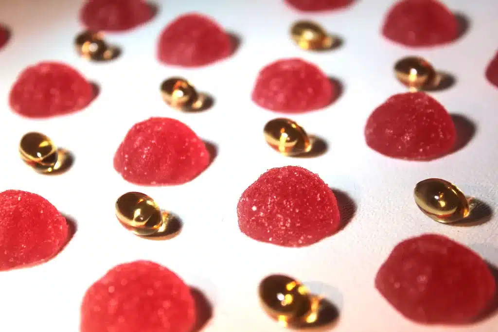 This is a close up of Nature's Candy strawberry lemonade CBD gummies and Nature's Candy CBD softgels arranged in a neat and attractive pattern, with soft lighting with close up to show texture.